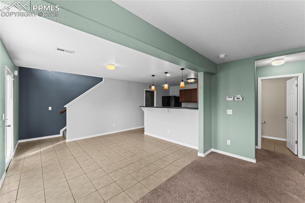 Image 9 of 30: Unfurnished living room with light tile patterned floors, stairway, a textu