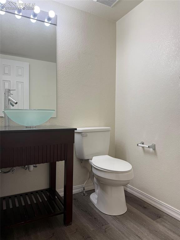 Image 10 of 34: Half bath featuring wood finished floors, toilet, baseboards, and a sink