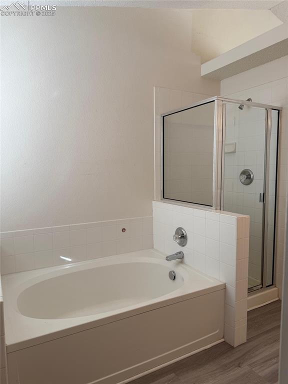 Image 14 of 34: Full bath with a stall shower, wood finished floors, and a garden tub