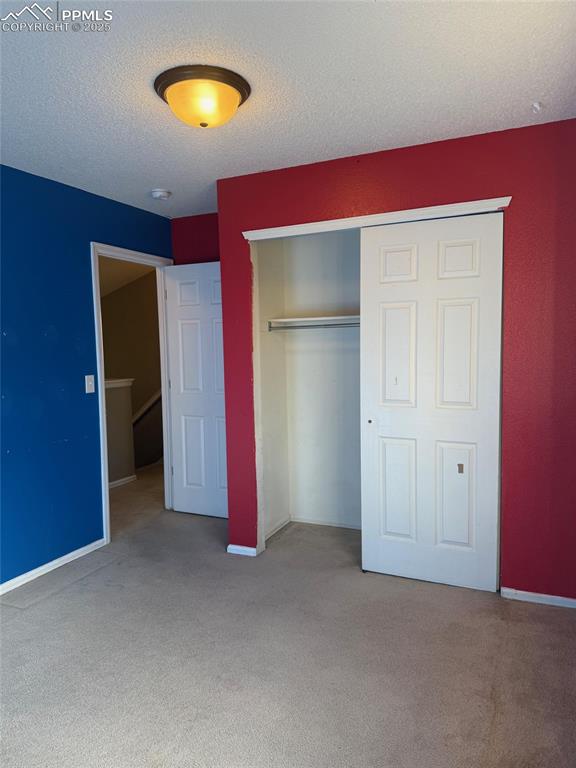 Image 18 of 34: Unfurnished bedroom with carpet floors, a closet, a textured ceiling, and b