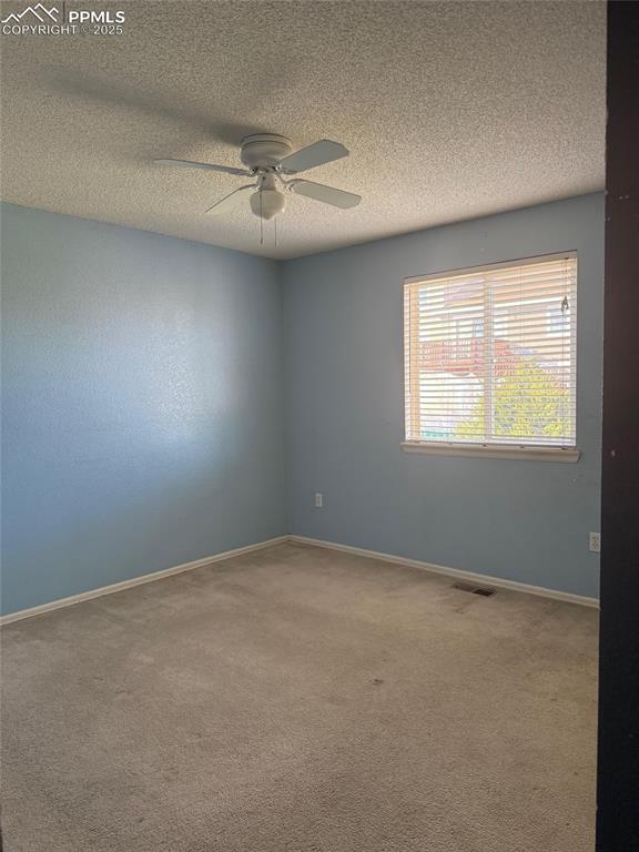 Image 19 of 34: Unfurnished room with carpet, ceiling fan, a textured ceiling, and baseboar