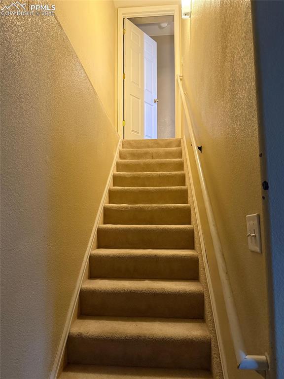 Image 27 of 34: Stairway with a textured wall and baseboards