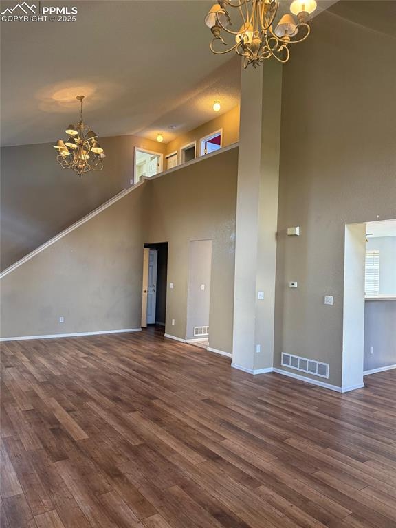 Image 4 of 34: Unfurnished living room featuring a chandelier, high vaulted ceiling, dark