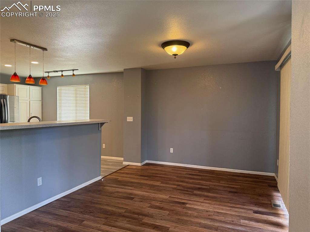 Image 6 of 34: Kitchen with dark wood finished floors, freestanding refrigerator, pendant