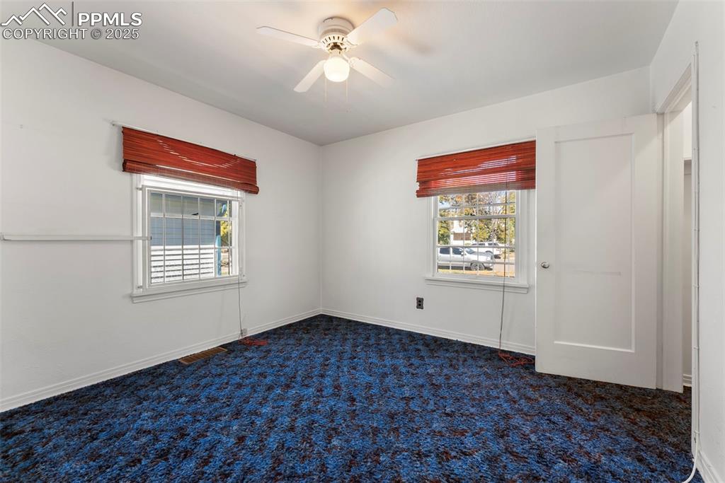 Image 12 of 30: Empty room featuring dark colored carpet and a ceiling fan