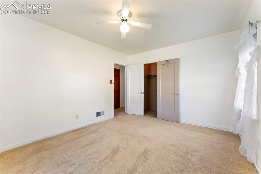 Image 17 of 30: Unfurnished bedroom featuring light carpet, ceiling fan, and a closet