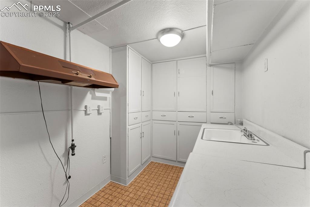 Image 18 of 30: Laundry area featuring a sink and a textured ceiling