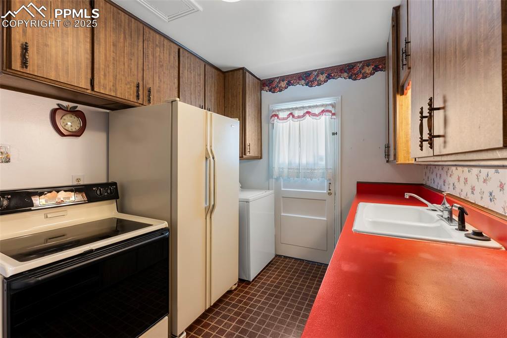 Image 3 of 30: Kitchen with range with electric stovetop, washer / dryer, and light counte