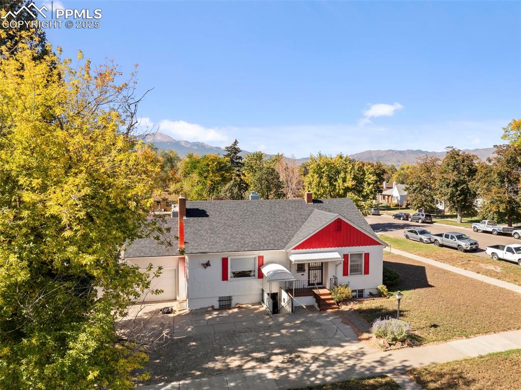 Image 30 of 30: View of front facade with a shingled roof, a mountain view, and a chimney