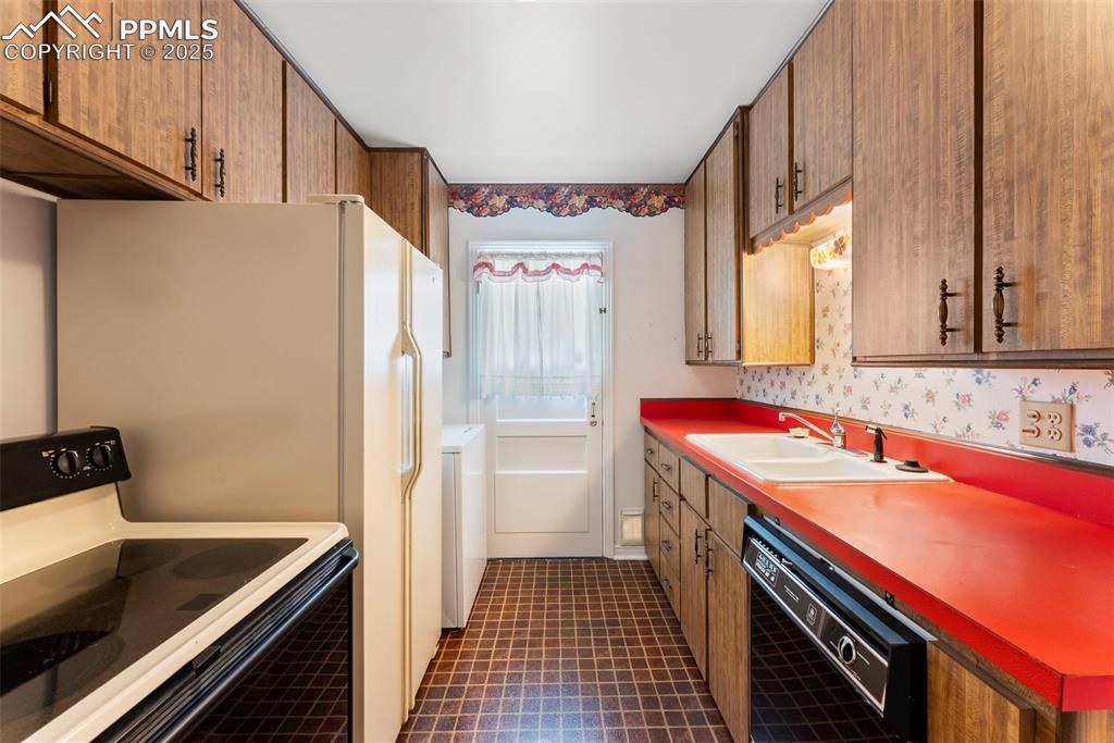 Image 5 of 30: Kitchen featuring white electric range, black dishwasher, brown cabinetry,
