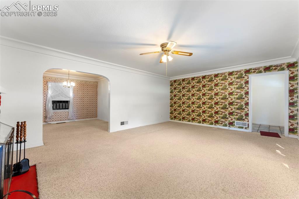Image 7 of 30: Carpeted empty room featuring wallpapered walls, a chandelier, ornamental m