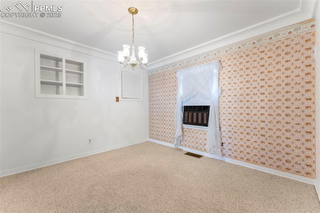 Image 8 of 30: Unfurnished room featuring carpet flooring, a chandelier, crown molding, an