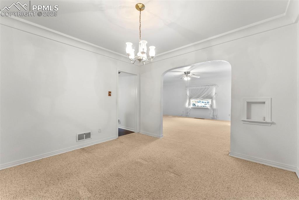Image 9 of 30: Spare room featuring crown molding, carpet floors, arched walkways, ceiling