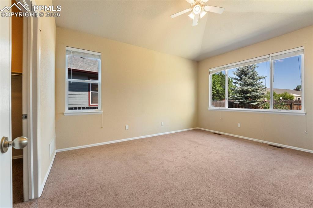 Image 19 of 39: Primary bedroom with ceiling fan, light carpet, plenty of natural light & l