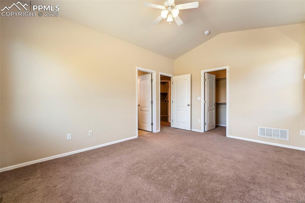Image 21 of 39: Unfurnished bedroom with a spacious closet, carpet floors, and ceiling fan