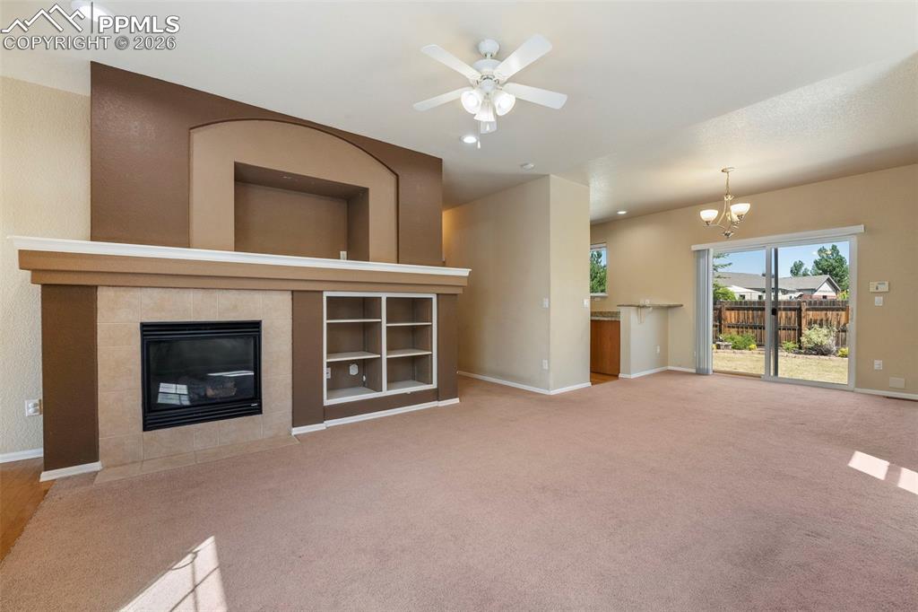 Image 8 of 39: Unfurnished living room featuring ceiling fan, a tiled fireplace, light col