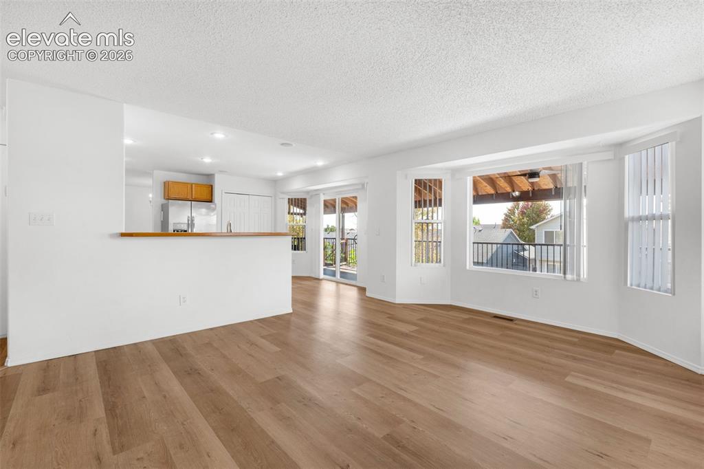 Image 10 of 48: Wood-finish flooring, recessed lighting, bay windows, and a sliding glass d