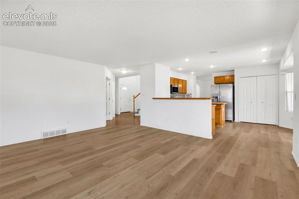 Image 11 of 48: Open-concept living space featuring wood-finish flooring, white walls, rece