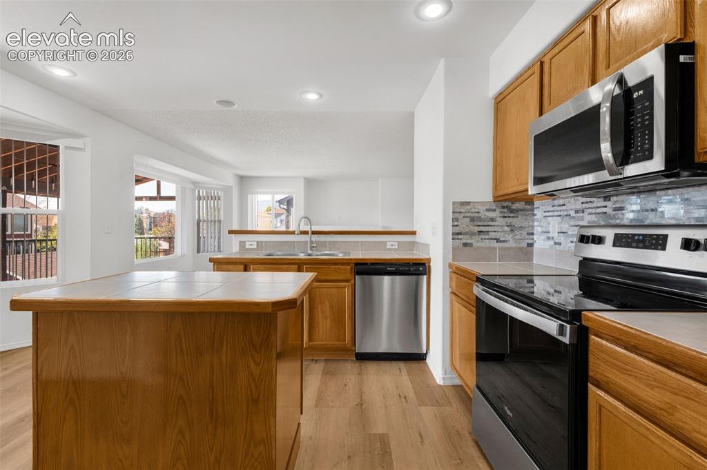 Image 13 of 48: Wood-finish flooring throughout, stainless steel appliances, tile backsplas