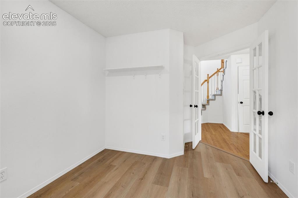 Image 18 of 48: Wood-finish flooring throughout, white walls, and a built-in white shelf