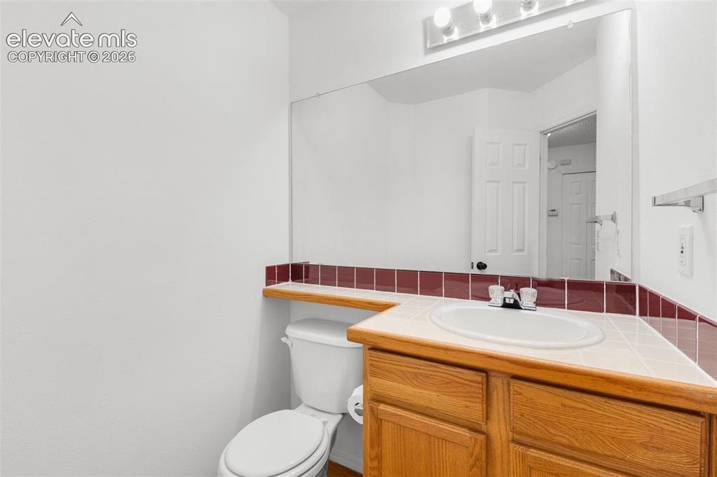 Image 19 of 48: Wood-finish vanity with an integrated sink and tiled countertop
