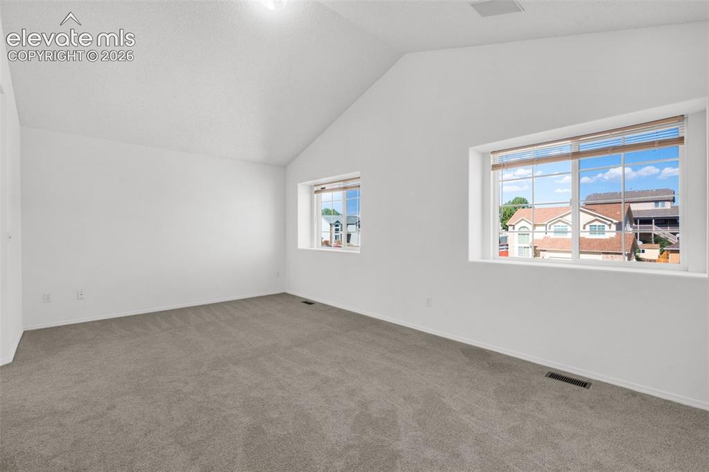 Image 20 of 48: Vaulted ceiling, two windows with blinds, light gray carpet, and white pain