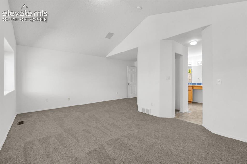 Image 22 of 48: White walls with vaulted ceiling, recessed ceiling speakers, gray carpeting