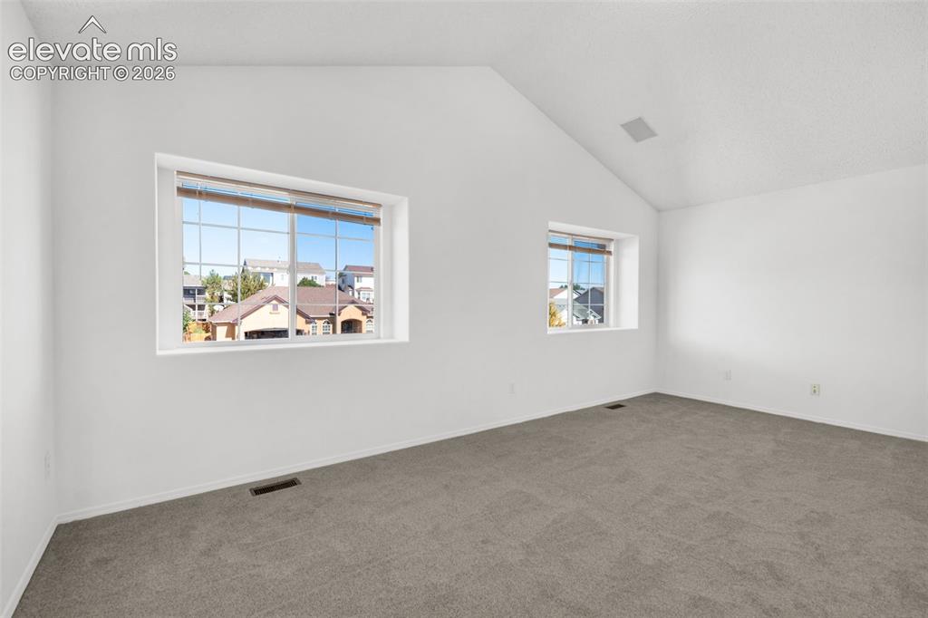 Image 23 of 48: Vaulted ceiling with an integrated speaker system, neutral gray carpeting,