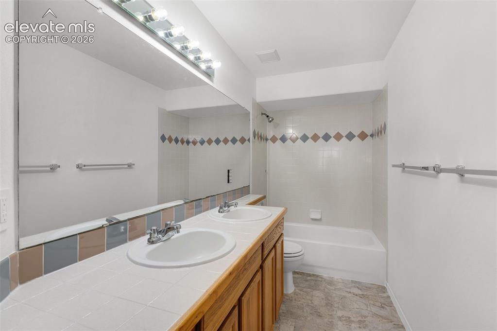 Image 29 of 48: Dual vanity with integrated sinks, wood-finish cabinetry, full-width mirror