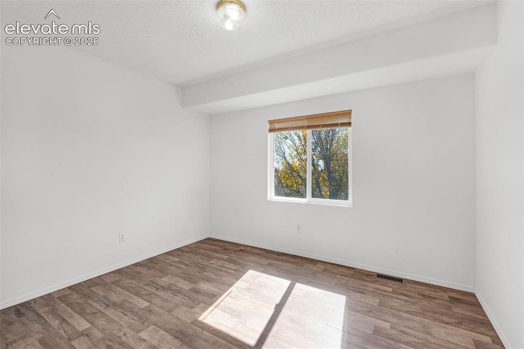 Image 30 of 48: Wood-finish flooring, single window with blinds, and flush mount ceiling li