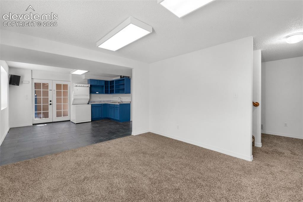 Image 33 of 48: Carpeted living area with white walls and overhead lighting