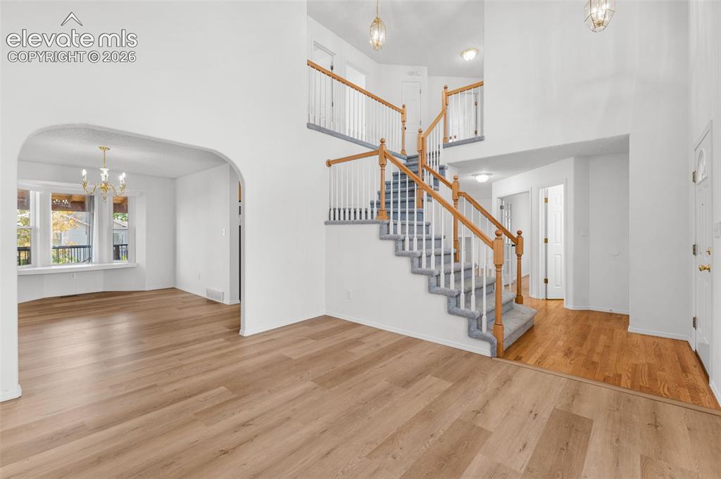 Image 4 of 48: Two-story entryway with a grand staircase and wood-finish flooring