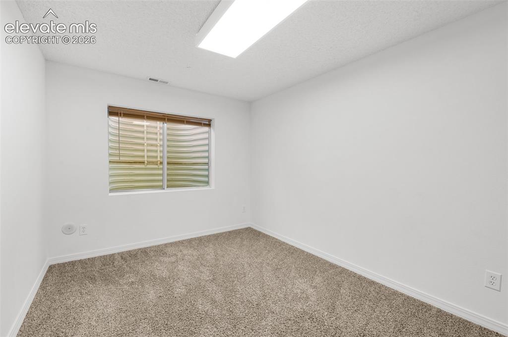 Image 40 of 48: Neutral wall finishes, textured carpeting, and a single window with blinds