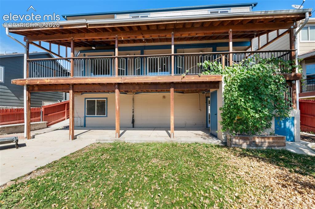 Image 43 of 48: Two-story wood-finish deck with dark railings, concrete patio, and ground-l