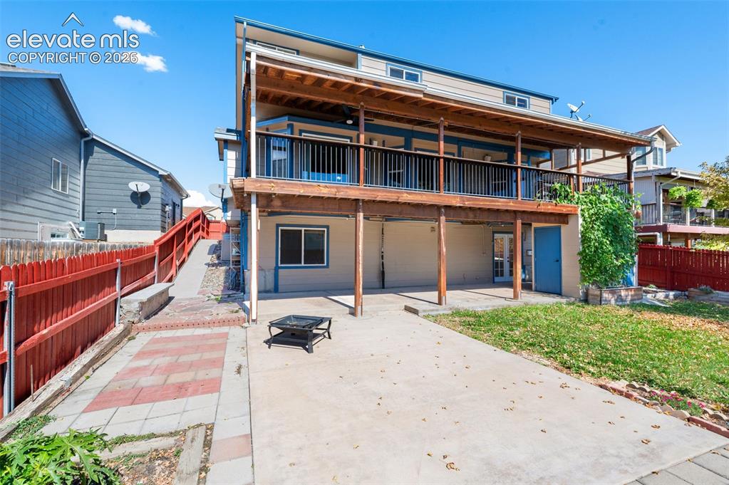 Image 44 of 48: Two-story structure with a covered balcony, wood railing, and exposed wood 