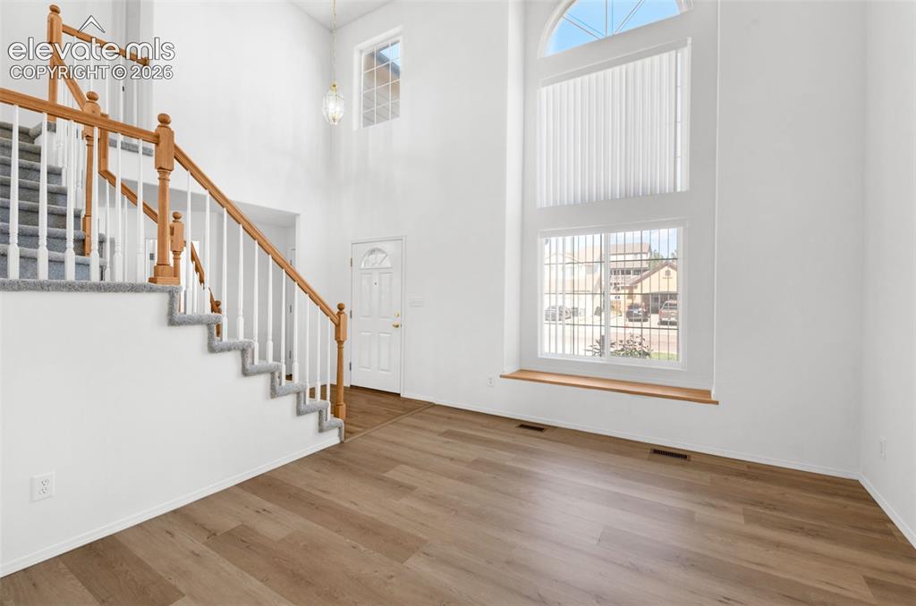 Image 5 of 48: Two-story entry with hardwood-finish flooring, a grand staircase with carpe
