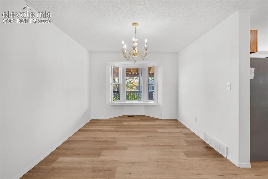 Image 6 of 48: Recessed bay window, brass-finish chandelier, wood-finish flooring, white p