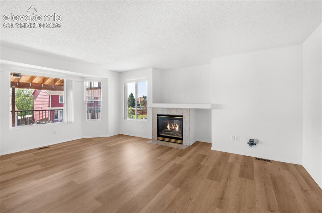 Image 8 of 48: Wood-finish flooring throughout, a gas fireplace with a tiled surround, and