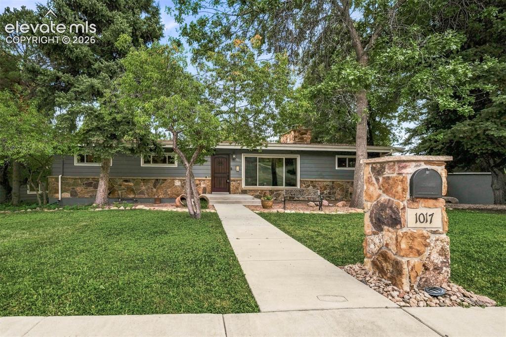 Caption: Front of home with mature trees and cement walk.