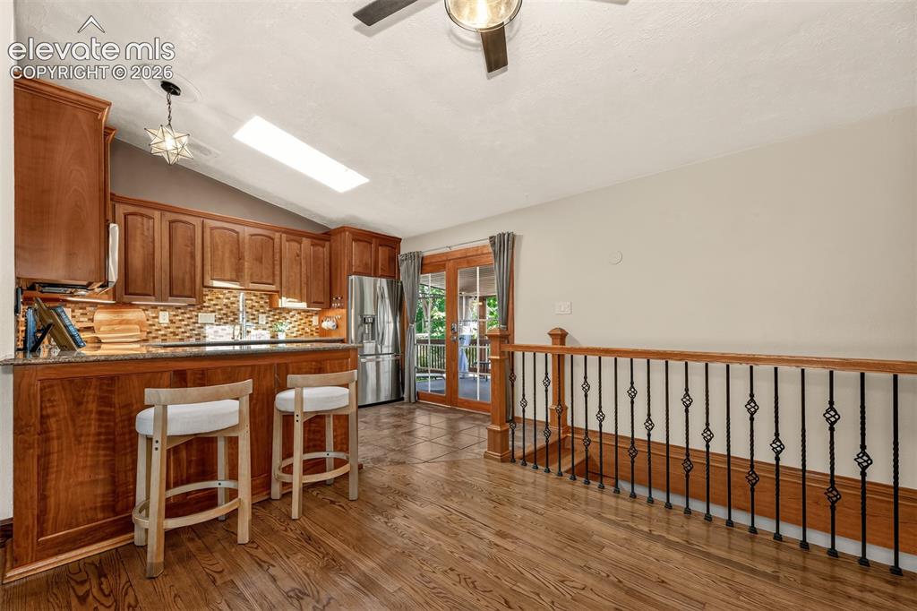Image 10 of 36: Kitchen with open space, hardwood floors, stairs down to the basement and w