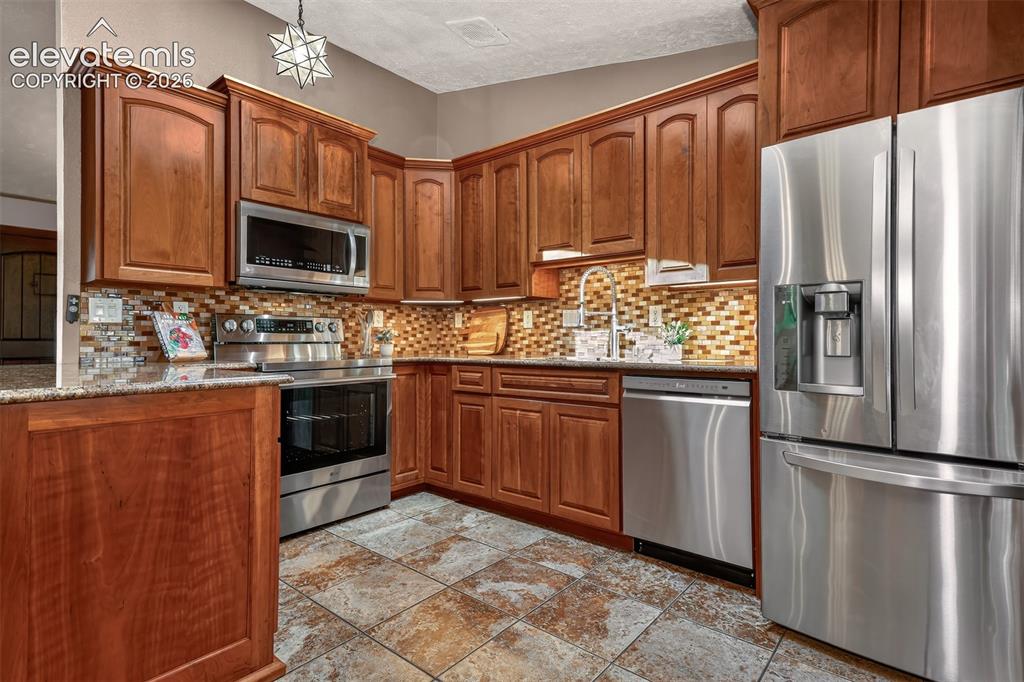 Image 11 of 36: Kitchen with granite countertops, stainless steel appliances tile flooring 