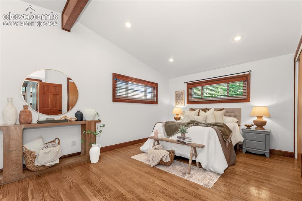 Image 13 of 36: Large primary bedroom with hardwood floors and seating area.