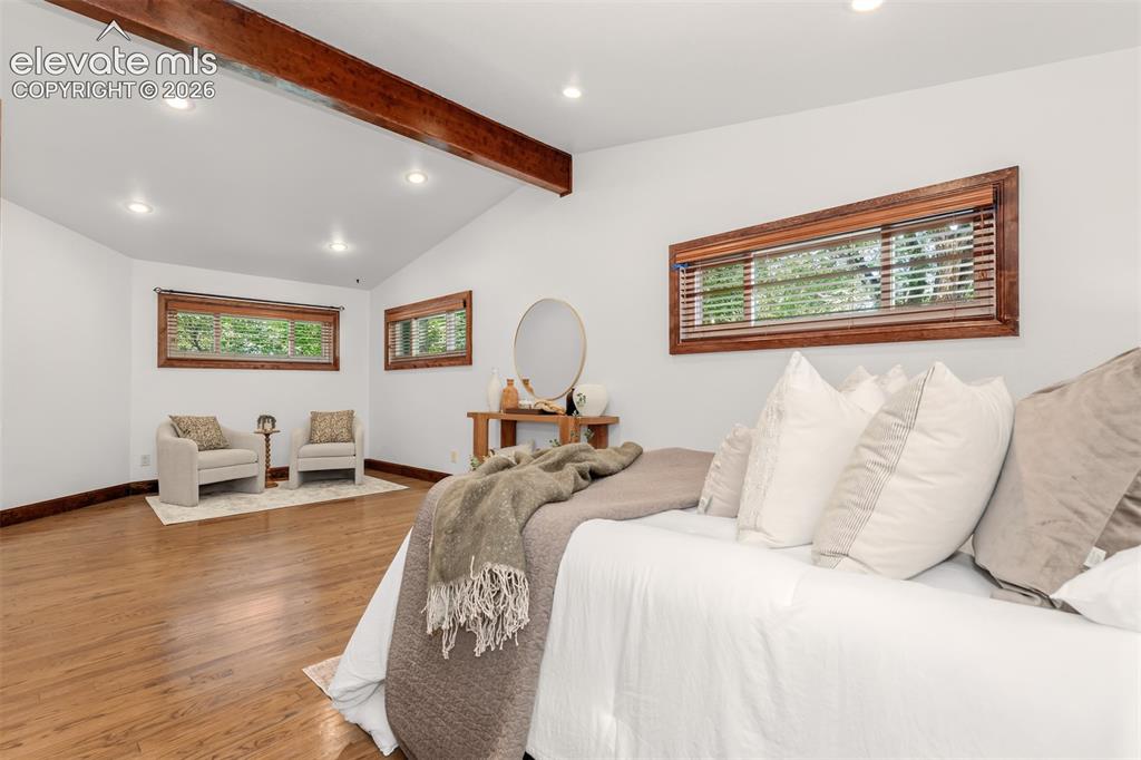 Image 14 of 36: Large primary bedroom with hardwood floors and seating area.