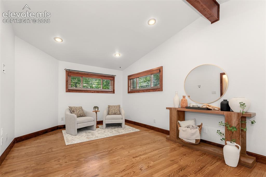 Image 15 of 36: Large primary bedroom with hardwood floors and seating area.