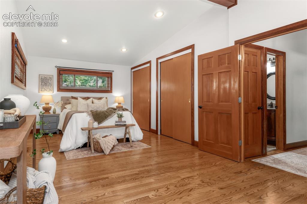 Image 16 of 36: Large primary bedroom with hardwood floors and seating area.