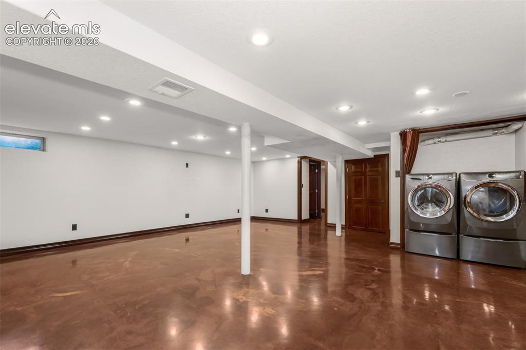 Image 20 of 36: Basement area with acrylic floors, laundry and second fireplace.