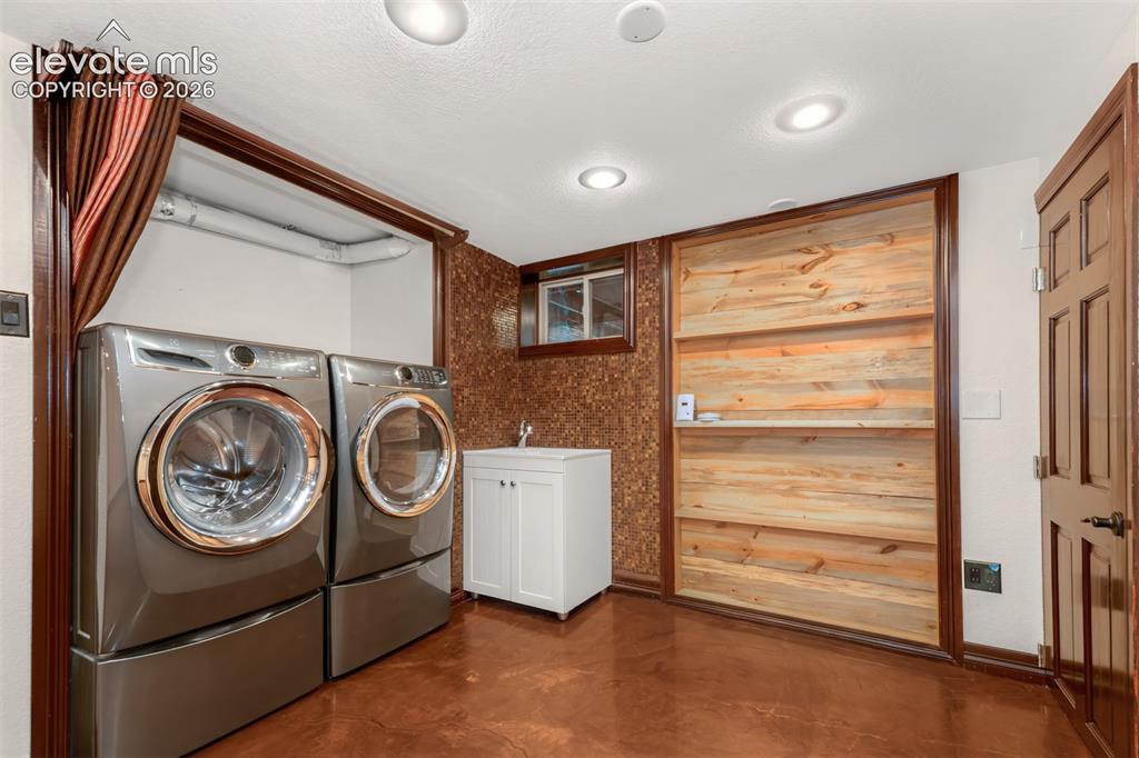 Image 21 of 36: Basement area with acrylic floors, laundry and second fireplace.