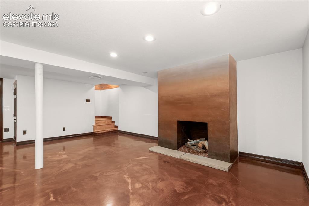 Image 22 of 36: Basement area with acrylic floors, laundry and second fireplace.