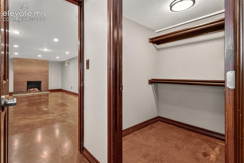 Image 26 of 36: Closet in basement, off bedroom, looking back towards family room with fire