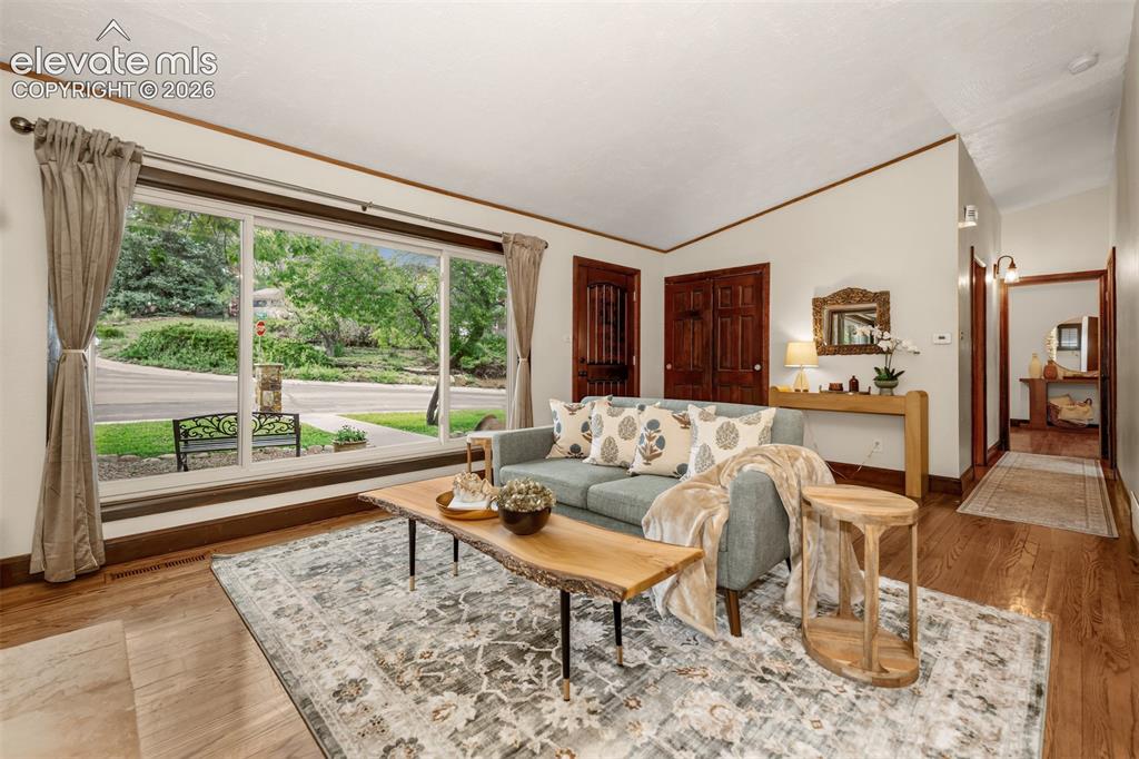 Image 6 of 36: Beautiful living room with large picture window, hardwood floors and firepl